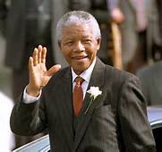 Nelson Mandela wearing a corsage, waves to crowd.