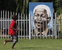 Nelson Mandela painting behind a fence with kids playing